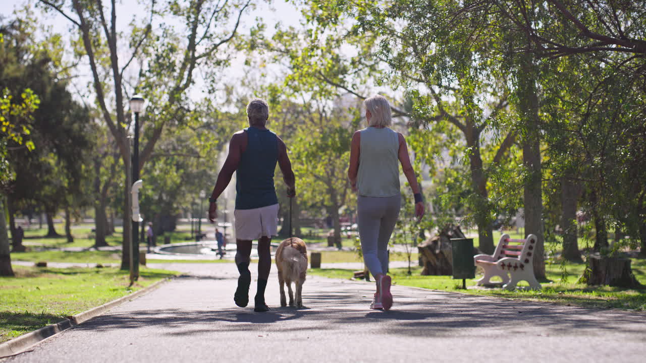 una pareja de mayores paseando a su perro en el parque
