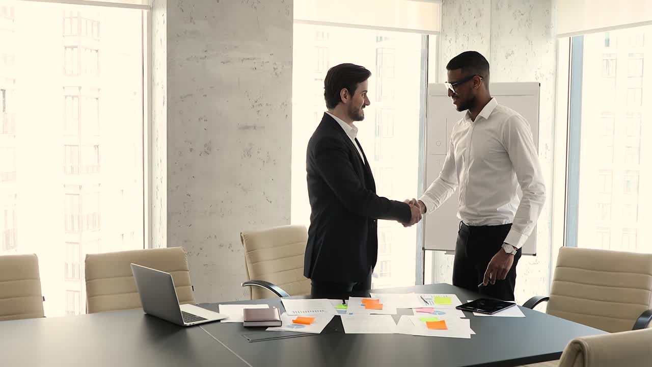 Two multiethnic businessmen shake hands accomplish business meeting