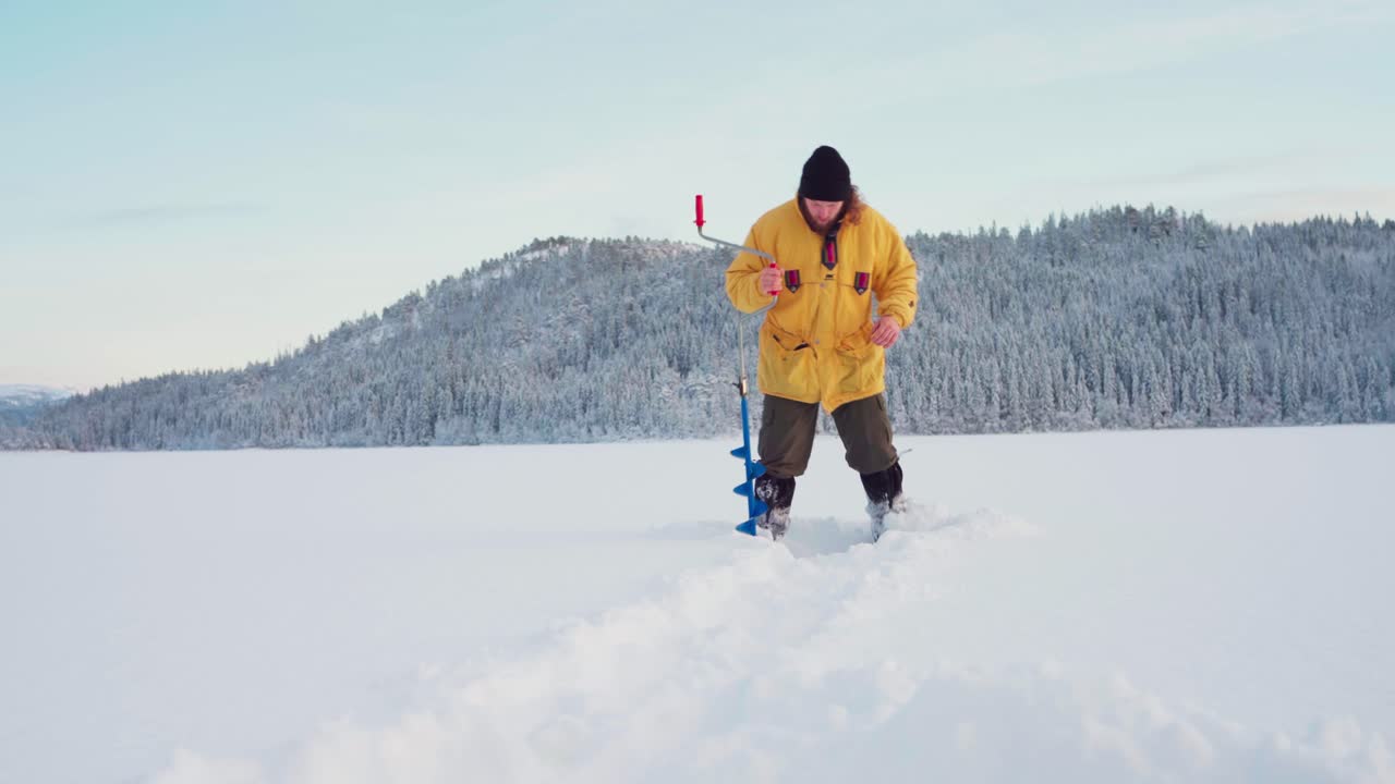 fisher macho perfora un agujero en el hielo con barrena de hielo