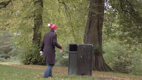 woman disposing plastic garbage in park bin