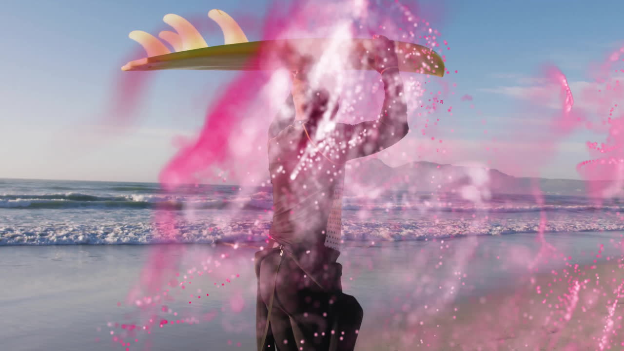 Surfer carrying board on beach with pink abstract animation overlay
