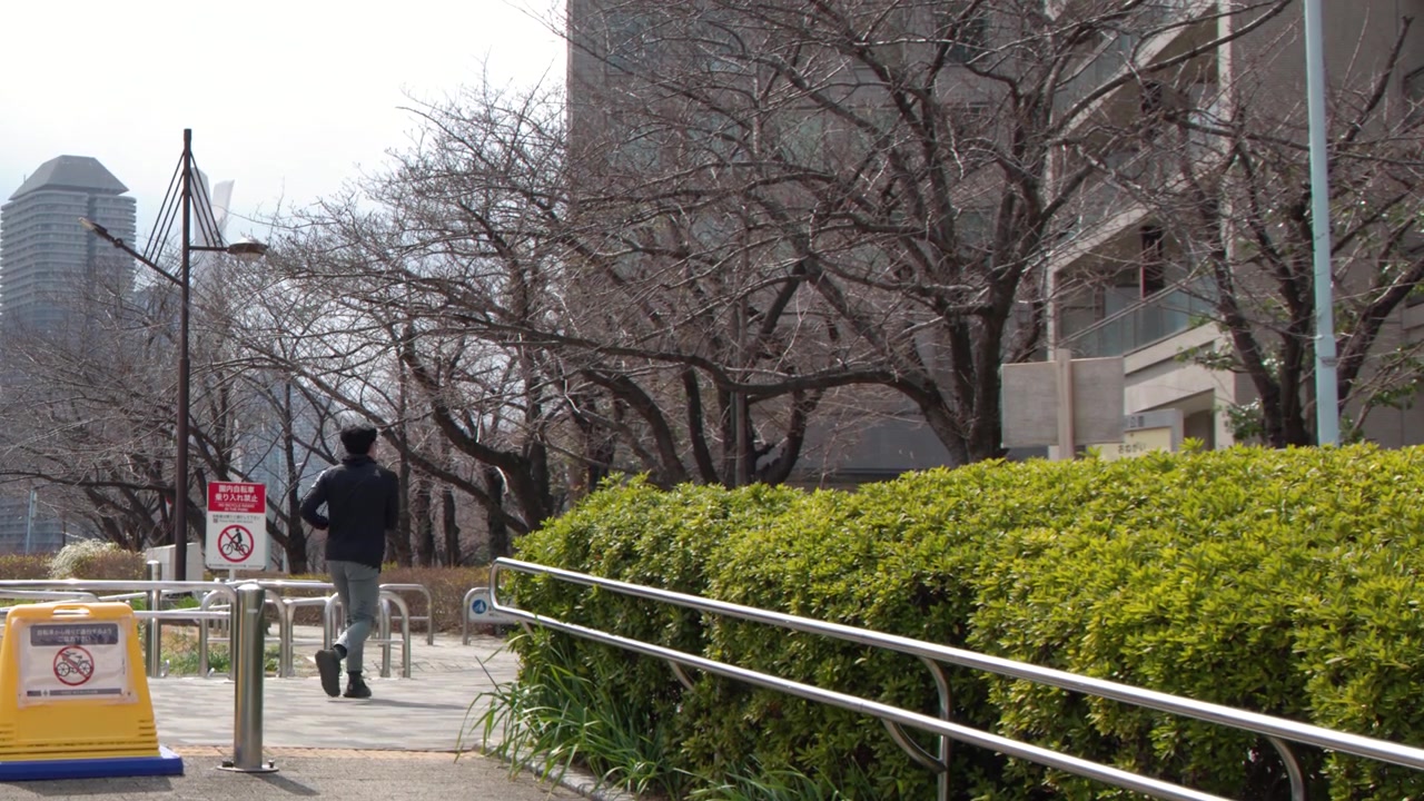 일본 도쿄의 고층 빌딩 근처 도시 공원 길을 달리는 활동적인 아시아 남성