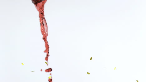 animation of confetti falling over red wine on white background