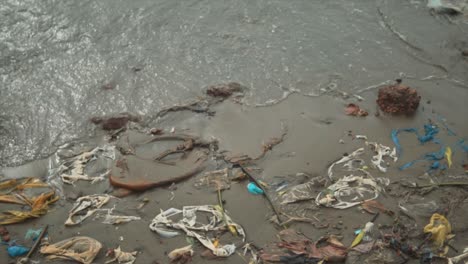 todavía tiro de basura y bolsas de plástico usadas en la arena en una orilla del río