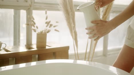 la femme se prépare à prendre un bain, versant de l'eau dans le tube de bain