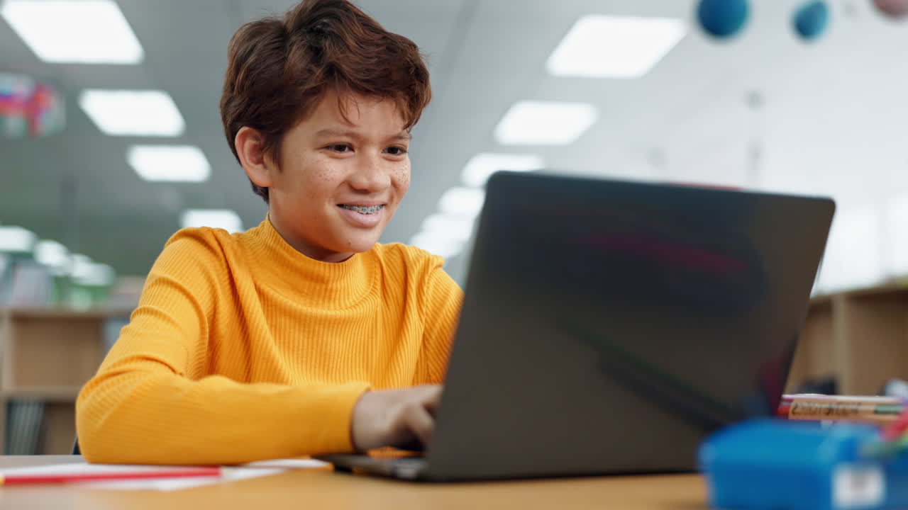 Boy with braces using laptop in classroom