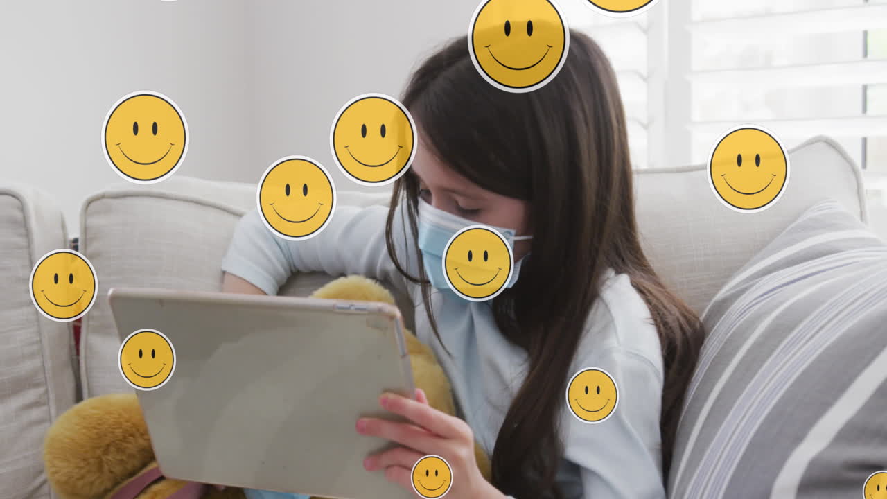 Animation of digital emoji icons over caucasian girl in face mask using tablet at home