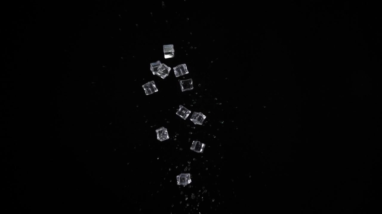 Cubetti di ghiaccio con acqua lanciati verso l'alto su sfondo nero