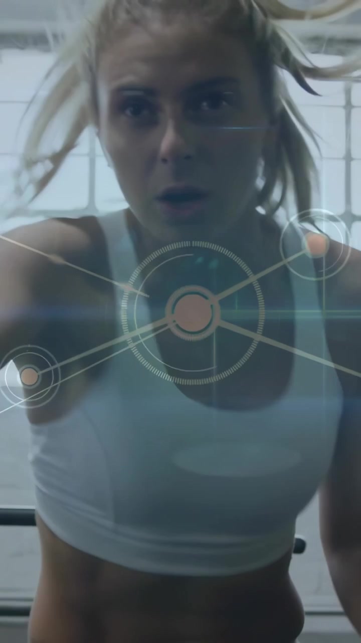 Female athlete initiating workout leaning over handlebars and pedaling in gym, HUD tracking effort