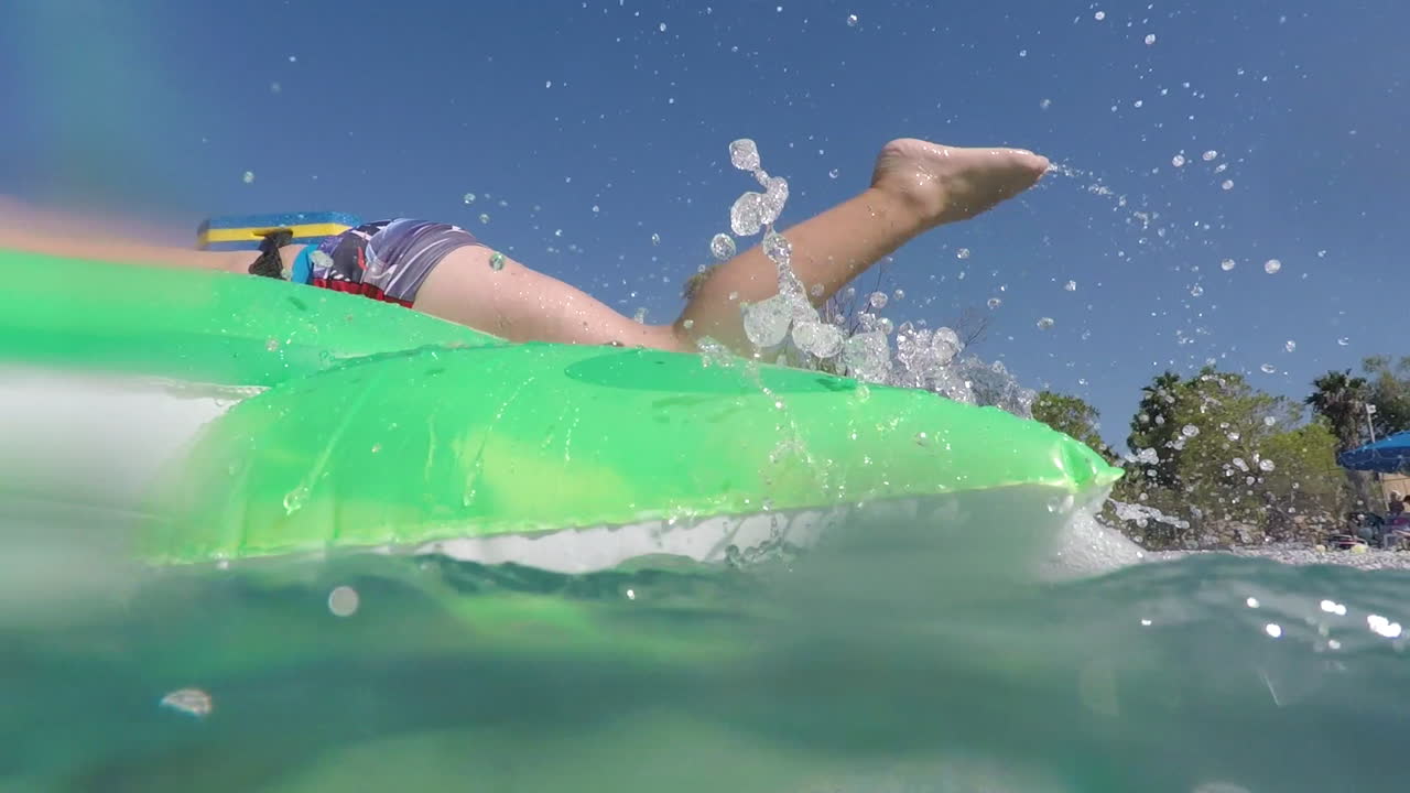 кавказский мальчик играет с надувной черепахой на пляже каламата, греция