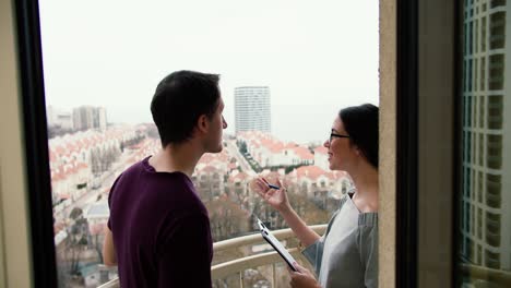 real estate agent shows stylish modern house to a man, a balcony with good view