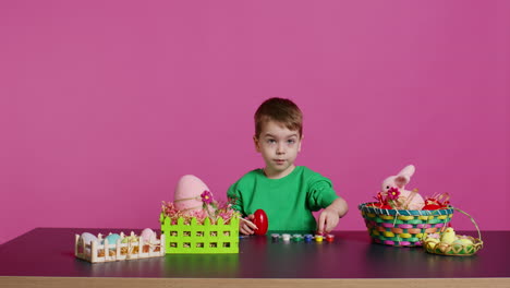 small sweet child decorating eggs with stamps and watercolor