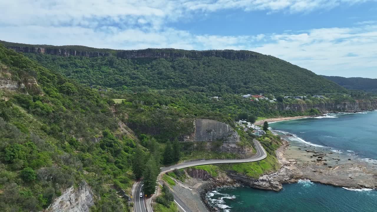 Aerial moving over holiday traffic on the Sea Cliff Bridge and towards Coalcliff town and beach