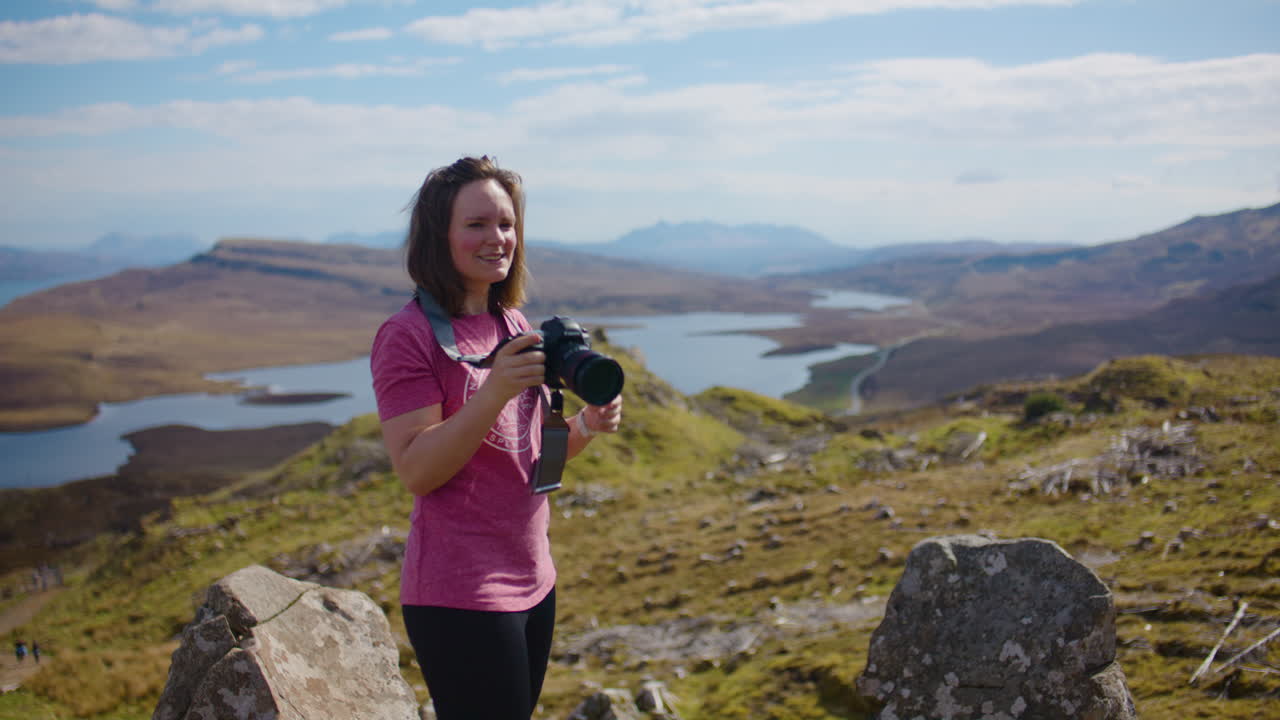 una mujer caucásica toma fotos desde un punto de vista panorámico en la isla de skye.