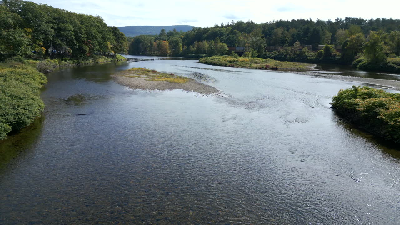 Drone soars above water of Mohawk Trail by Deerfield River in Western Massachusetts New England USA