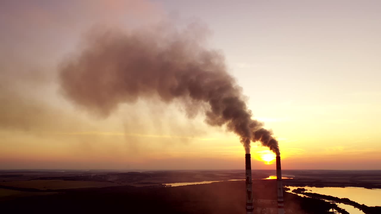 Pollution the atmosphere. Two factory pipes throw dirty emissions. Smoke looks beautiful but dangerous at sunset. Power plant on the beautiful landscape in the evening.
