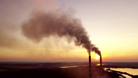 pollution the atmosphere. two factory pipes throw dirty emissions. smoke looks beautiful but dangerous at sunset. power plant on the beautiful landscape in the evening.