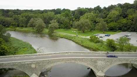 drone flying along a toronto river with a bridge on an overcast summer day