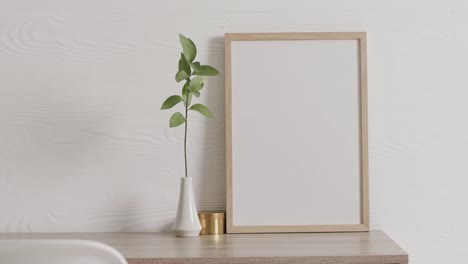 marco de madera con espacio de copia en fondo blanco con planta en el escritorio contra la pared blanca