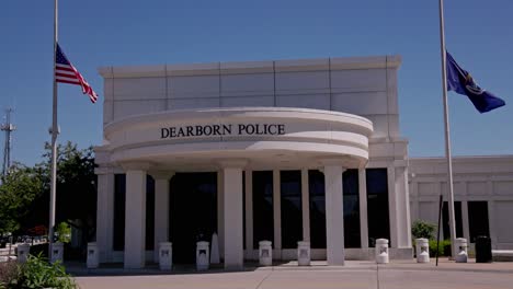 Dearborn,-Michigan-police-department-building-with-American-and-Michigan-flags-flying-at-half-staff-with-stable-video