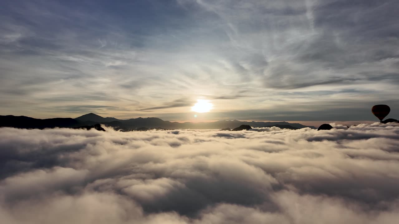 Hot air balloons rising above a sea of clouds with mountains during sunrise in Vang Vieng, Laos