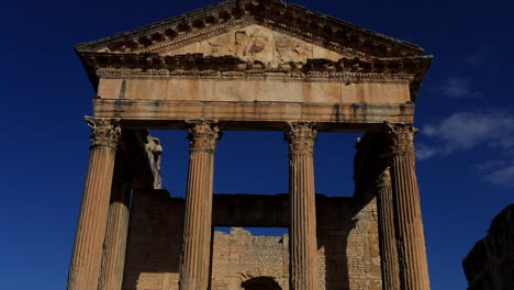 sunlit roman columns of dougga against a clear blue sky