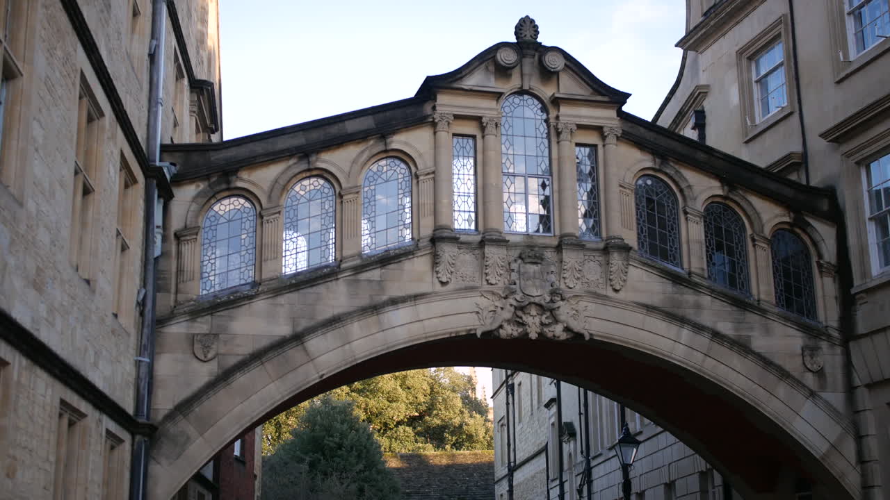 Un ponte dei sospiri storico in pietra con finestre ad arco ornate collega due edifici universitari a Oxford, ideale per progetti accademici, turistici o a tema patrimonio che mostrano l'architettura classica britannica.