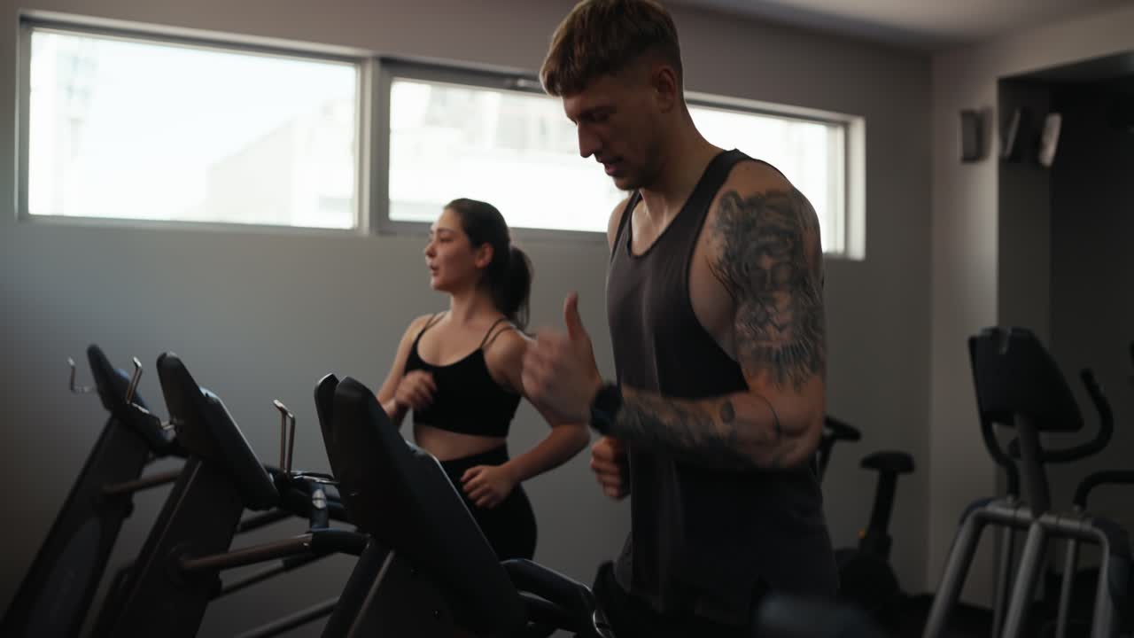Un uomo e una donna che corrono sui tapis roulants in palestra