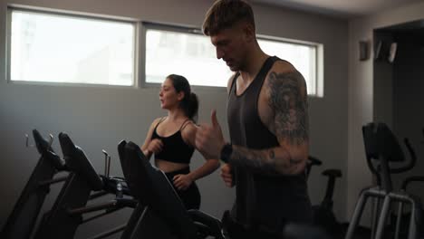 a man and woman running on treadmills at the gym