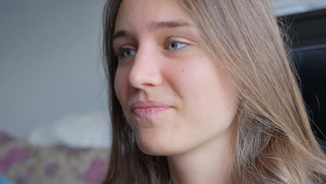 Close-up-of-woman-smiling-and-listening-while-looking-into-camera