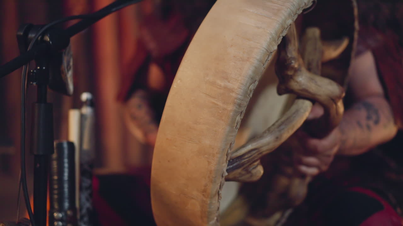 el músico toca el tambor chamánico con un palo peludo en toda la cabina