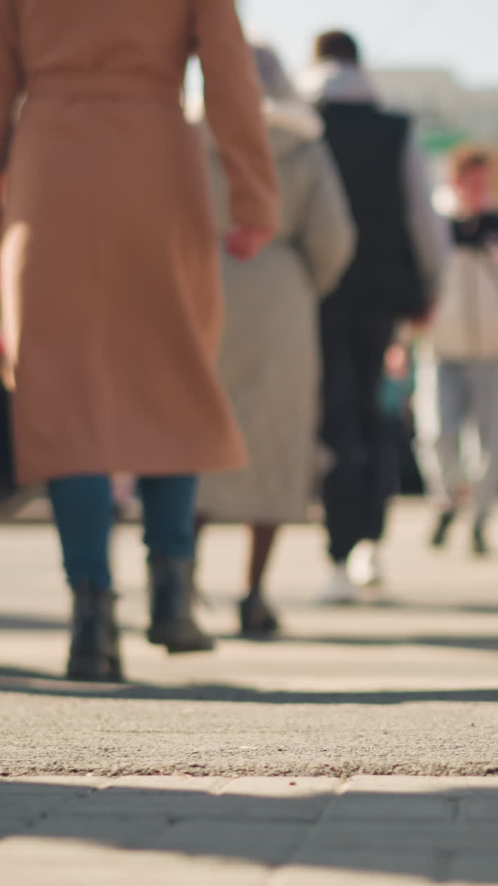 Uomo bianco che cammina su un marciapiede affollato, vista posteriore con messa a fuoco su passo e suola, persone con cappotti lunghi e stivali, ritmo frenetico del tragitto casa-lavoro, traffico e vetrine sfocati, acquirente e impiegato