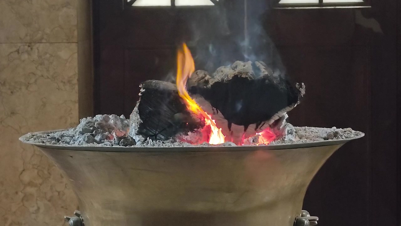 Ceppi di legno che bruciano in un braciere decorativo di metallo.