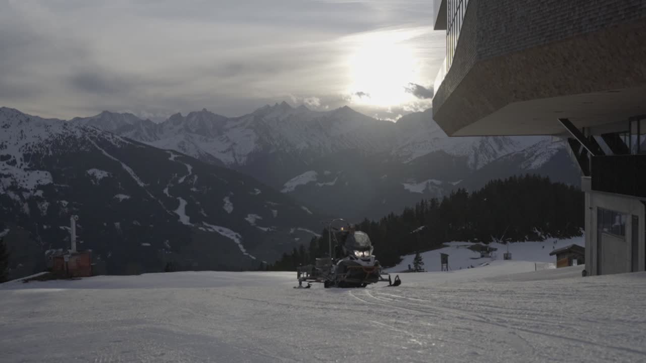 Snowmobile during the sunrise in closed ski resort, very early in the morning in mountains. Austrian Alps in the winter.