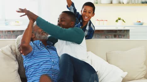 Grandfather,-father-and-son-cheering-while-watching-tv