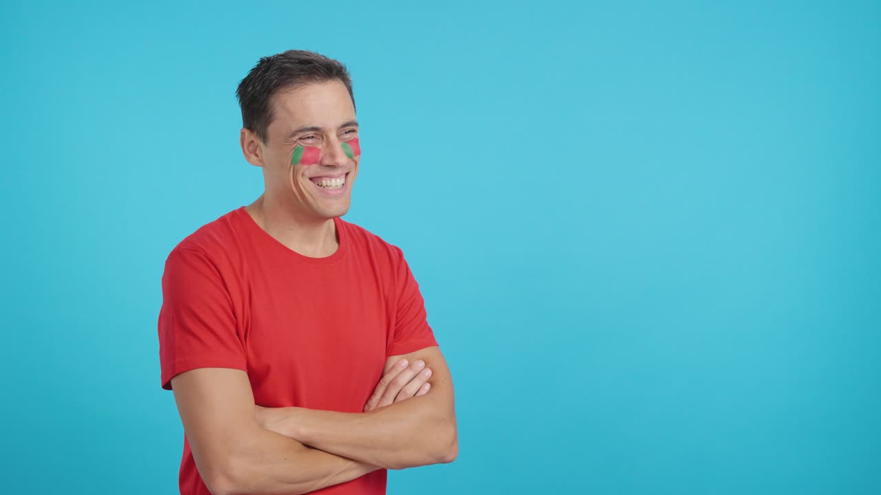 Happy man with portuguese flag painted on face looking away
