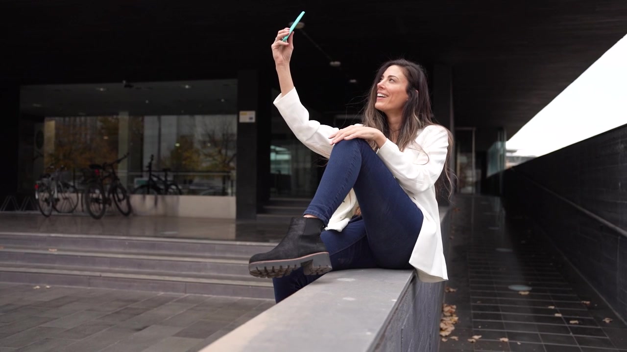 Una giovane donna si sta scattando un selfie all'aperto in un contesto urbano moderno, pieno di vita e vivacità.
