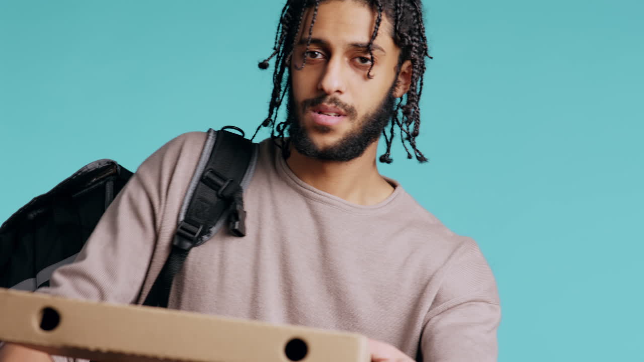 Portrait of BIPOC courier delivering pizza order to client, camera background