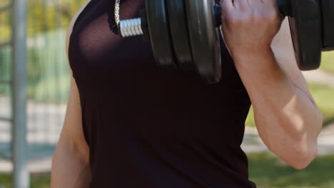 close-up athletic man doing arms weight lifting dumbbells exercises, pumping up arm bicep muscles