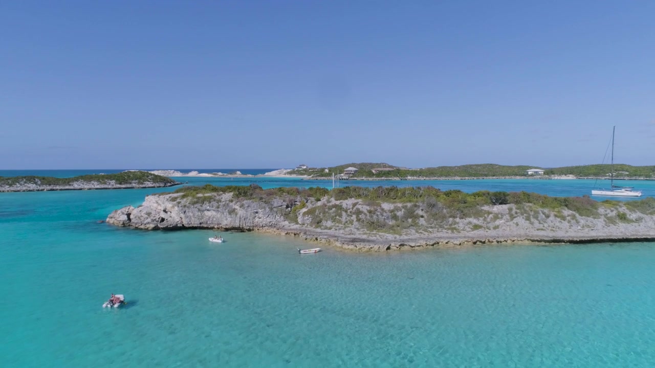 Vista aerea con drone di isolotti isolati delle Bahamas con barche a vela e acqua cristallina.