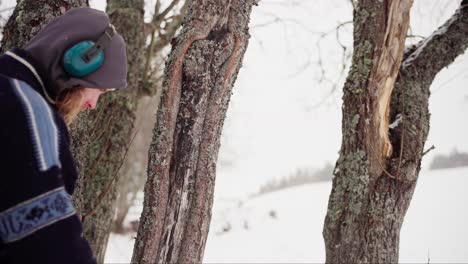 norwegian guy with headphones checking old tree barks during winter