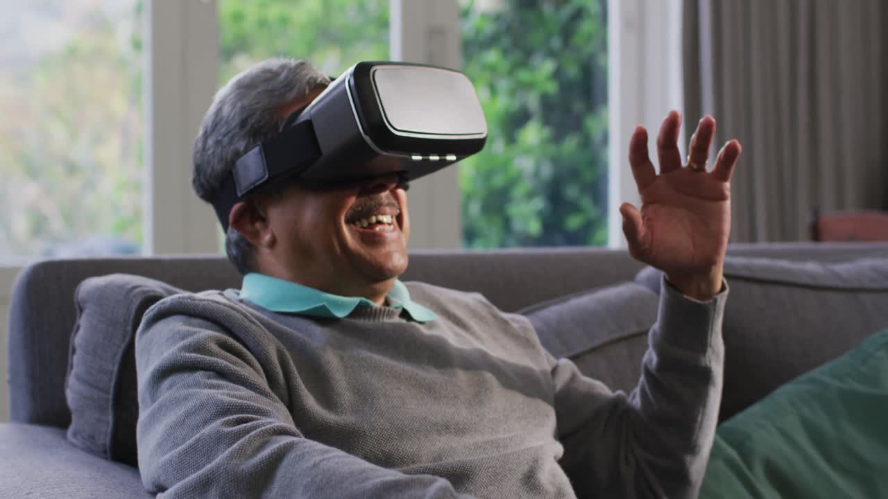 Happy mixed race senior man wearing vr headset and having fun at home