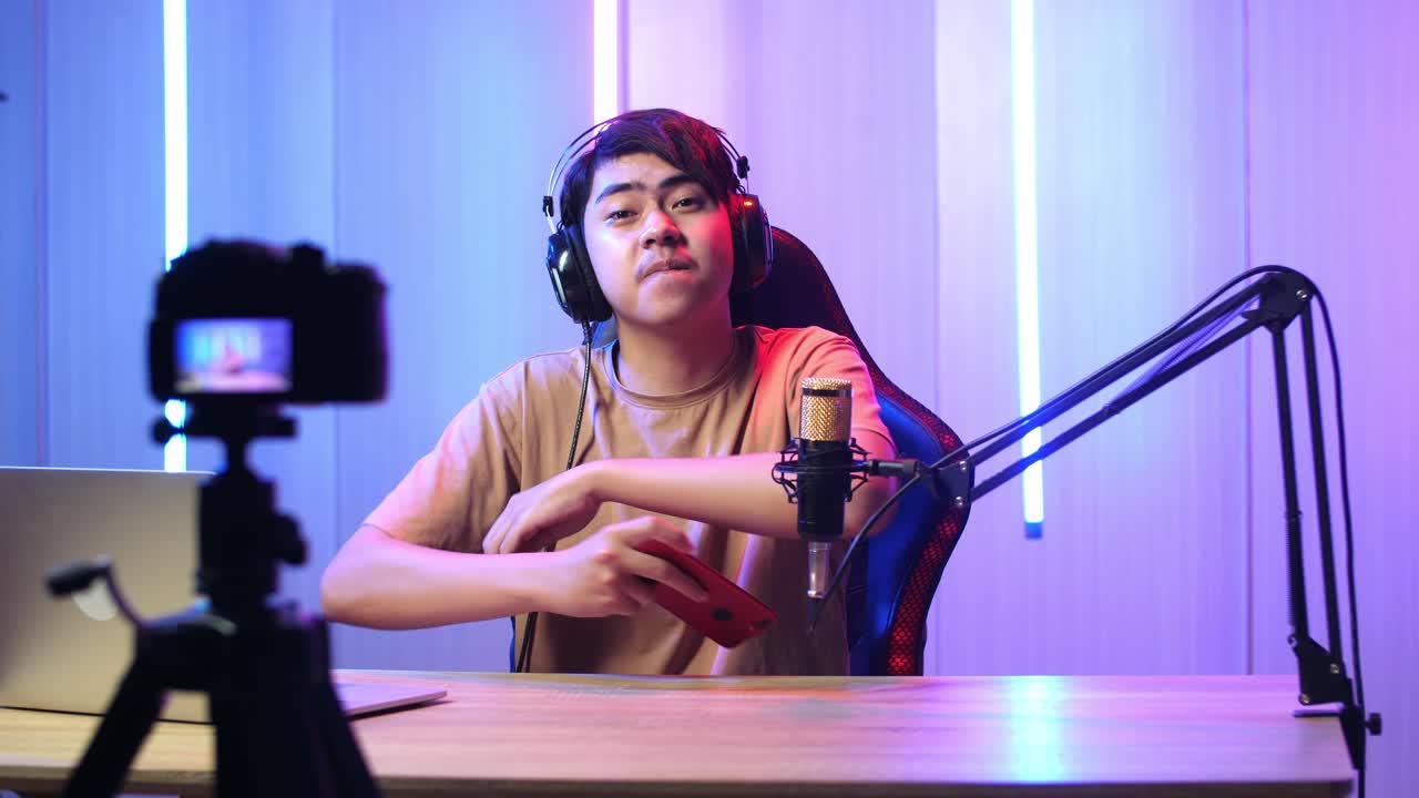 Asian Man Playing Video Game With Mobile Phone Then Pose And Smiles To Camera While Live Stream