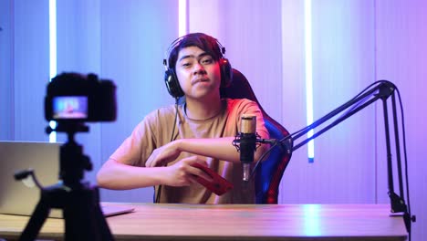 asian man playing video game with mobile phone then pose and smiles to camera while live stream