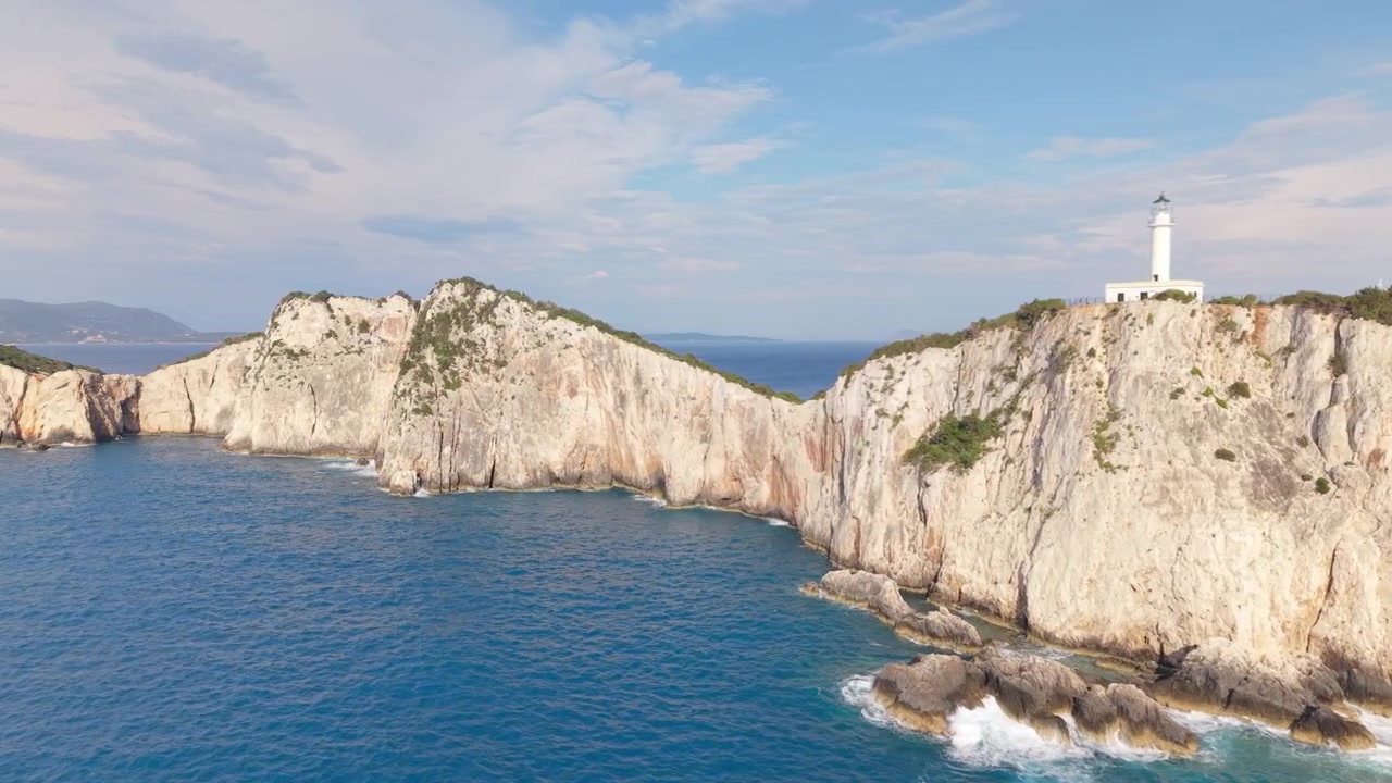 Sorvolo con drone lungo le scogliere drammatiche di Capo Lefkatas sull'isola di Lefkada, Grecia. Faro mozzafiato, Mar Ionio cristallino, costa frastagliata e paesaggio mediterraneo da togliere il fiato