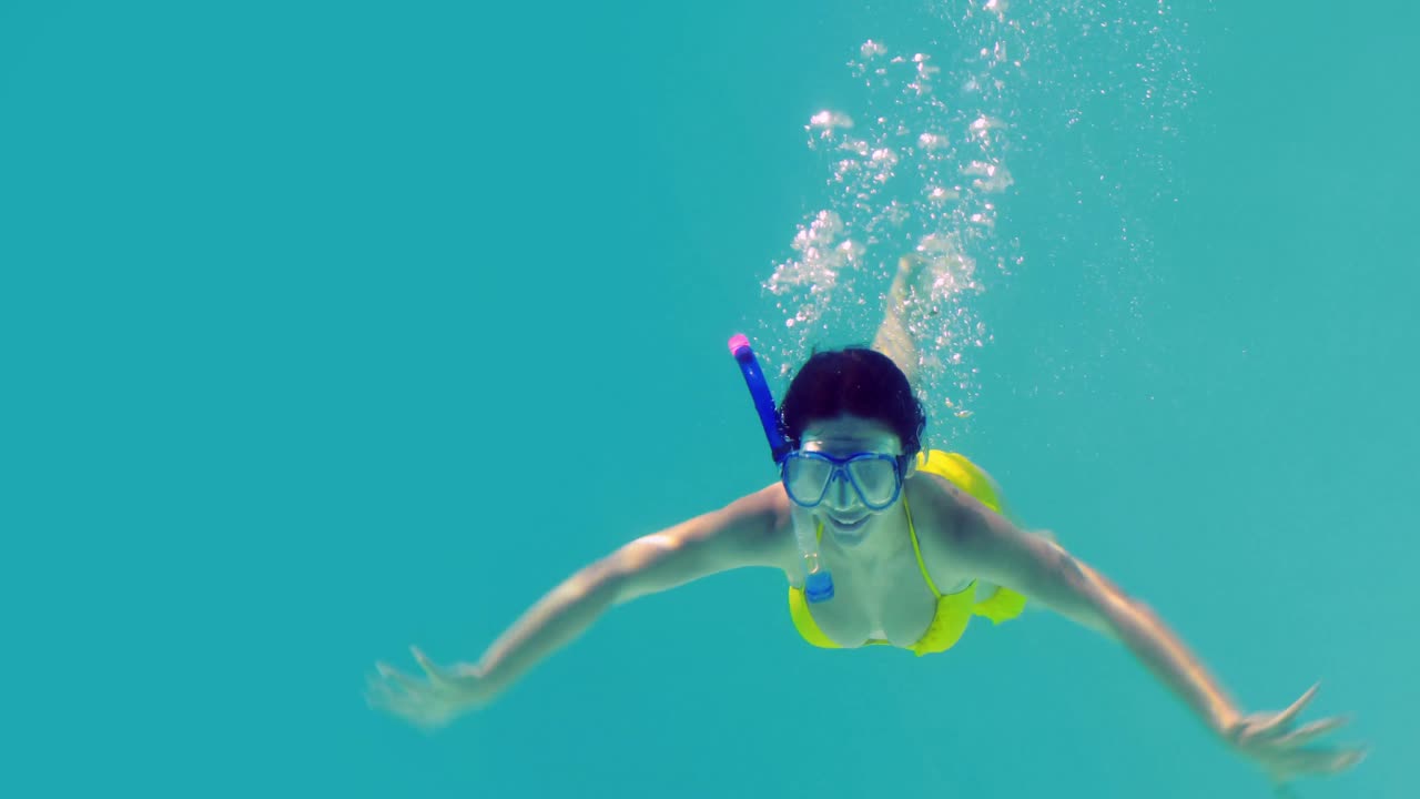 스노클을 입고 수영장에 뛰어드는 예쁜 갈색 여자