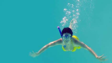 pretty brunette diving into swimming pool wearing snorkel