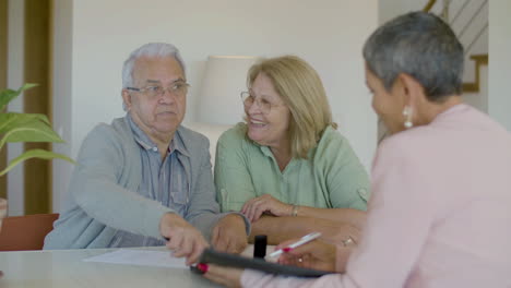 senior couple sitting at table, talking with realtor and discussing details of agreement