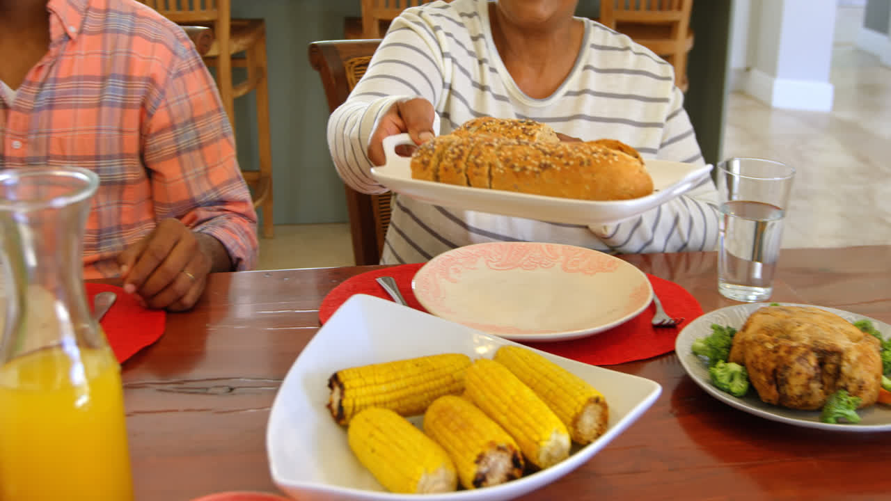 vista de la familia negra teniendo comida en la mesa de comedor en un hogar cómodo 4k