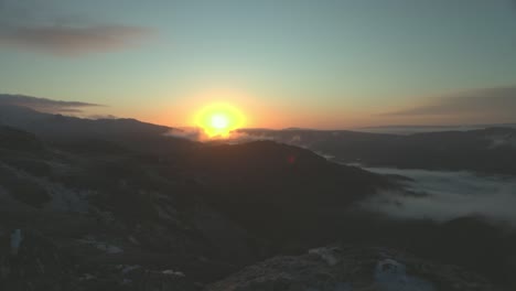 Static-shot-of-the-sun-rising-from-behind-the-mountain-range-from-Ben-A'an